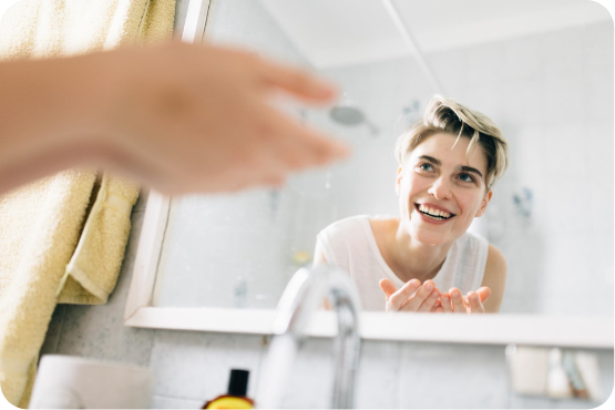 woman's reflection in mirror washing face