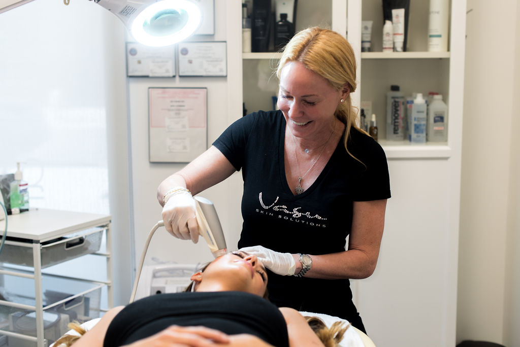Jen giving a Facial with laser to woman lying on table