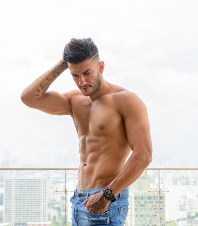 Young handsome muscular shirtless man looking down toward smooth chest